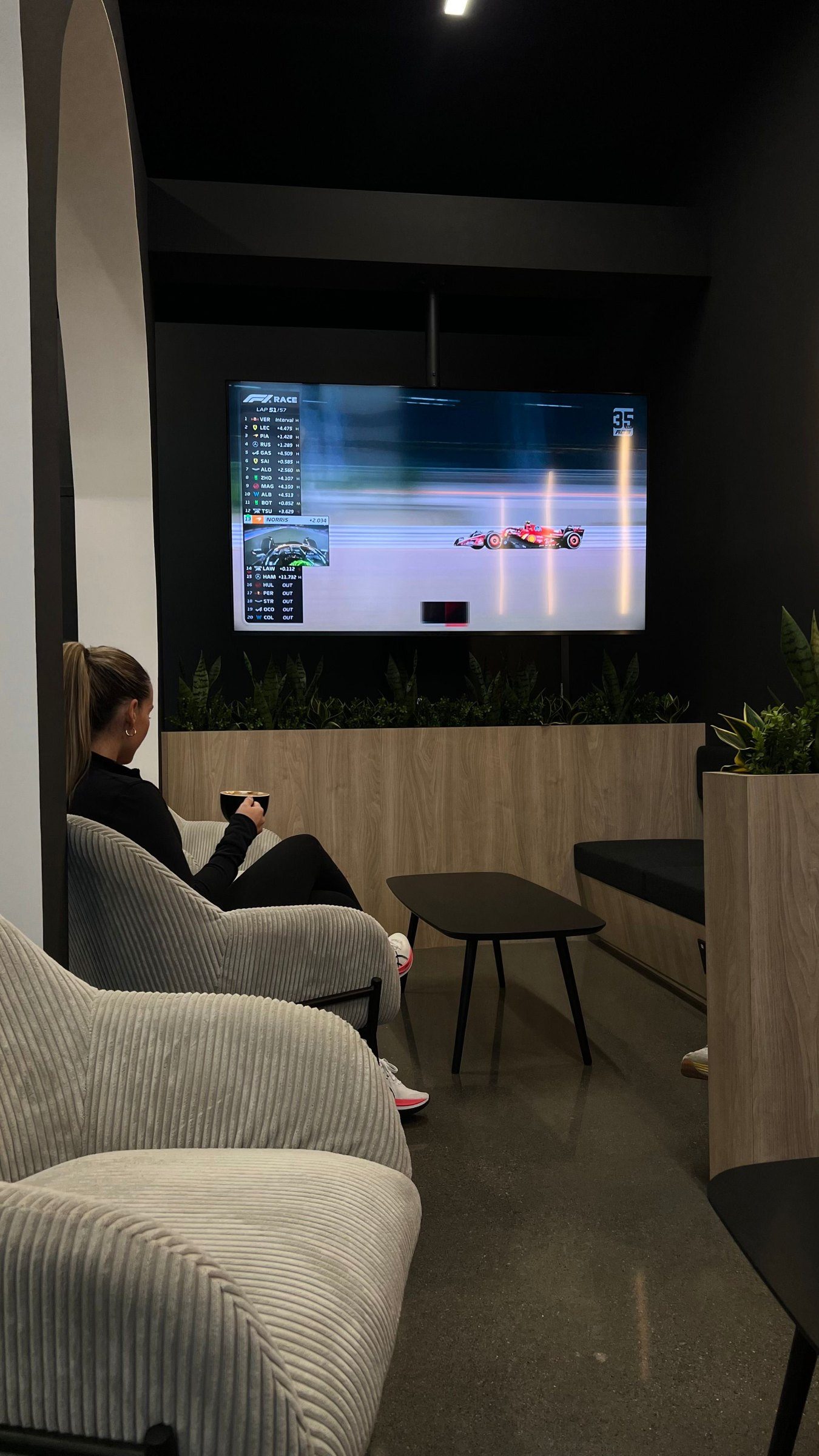 Une cliente prend son café dans le lounge, une course à la télé